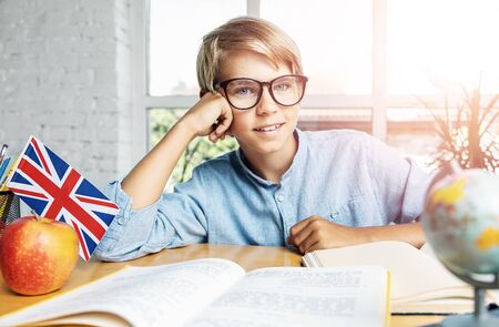 Portrait of teenage schoolboy in spectacles preparing for exam in englishの写真素材