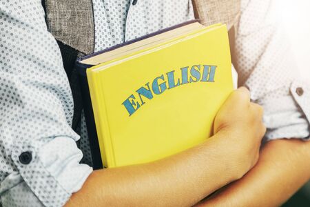 Boy with backpack holding English books closeupの写真素材