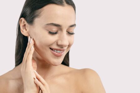 Close-up portrait of cute brunette feeling her soft skin with eyes closed isolated white background copyspaceの写真素材