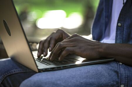 Closeup of african male working by laptop outdoorsの写真素材