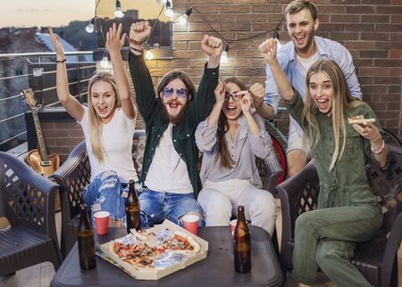 Best friends having beer, eating pizza and watching football showing genuine emotionsの写真素材