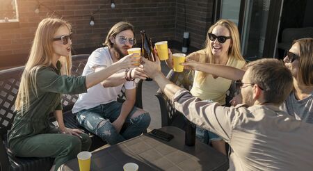 Group of friends touch glasses as they have their Friday beer partyの写真素材