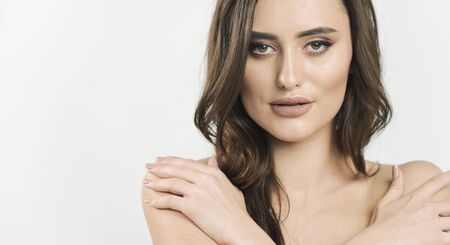 Portrait of skittish brown hair young beauty hugging her naked shoulders isolated white background copyspaceの写真素材