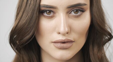 Closeup portrait of an attractive brunette young woman with brown eyes and wavy hair isolated white backgroundの写真素材