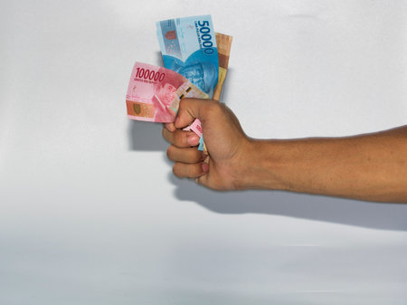 Hand holding a bunch of banknotes isolated on a white background.のeditorial素材