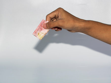 Hand holding money isolated on white background with clipping path and shadow.のeditorial素材