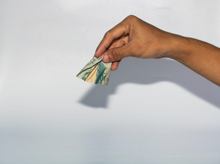 Hand holding money isolated on white background with clipping path and shadow.のeditorial素材