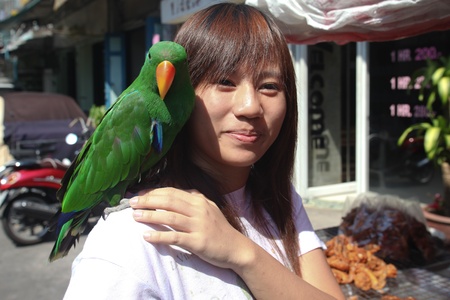 BANGKOK - JANUARY 14. Woman with green parrot on shoulder bought in Chatuchak market on January 14, 2012 in Bangkok, Thailand. Chatuchak is Thailandのeditorial素材