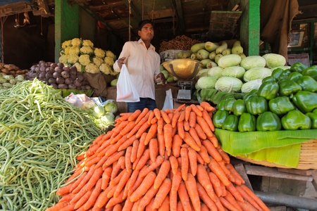 MYSORE â JANUARY 29 : Indian vegetable merchant is selling two carrots on his stand in Mysore city market on January 29, 2011.のeditorial素材