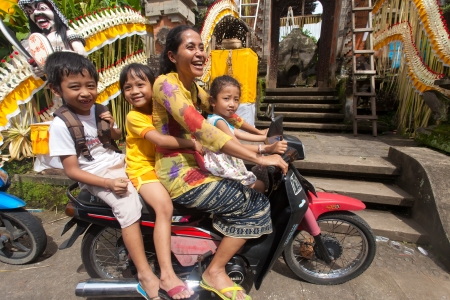 BALI - JANUARY 20. Woman driving her kids to school motorcycle on January 20, 2012 in Bali, Indonesia. Common Balinese cannot afford cars to transport their family.のeditorial素材