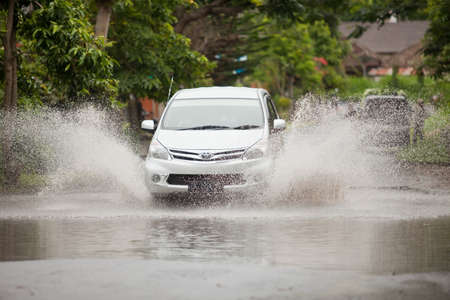 LAKE BATUR, BALI - JANUARY 21. Car driving through flooded street after downpour on Lake Batur on January 21, 2012 in Bali, Indonesia. Weather patterns have changed in recent years.のeditorial素材