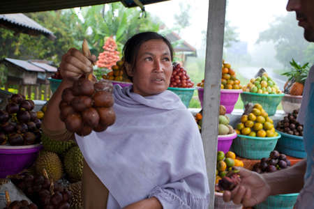 BALI - JANUARY 20. Balinese fruit stall owner selling her produce in Bali on January 20, 2012 in Bali, Indonesia. Most fruit is used for offerings in temples rather for personal consumption.のeditorial素材