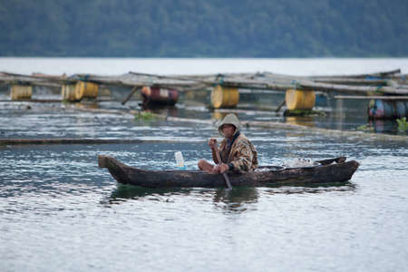 LAKE BATUR, BALI - JANUARY 22. Man fishing in boat on Lake Batur on January 22, 2012 in Bali, Indonesia. Fish is part of the stape diet on the lake.のeditorial素材