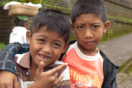 BALI - JANUARY 22. Young Balinese boys selling offerings to pilgrims at Mother Temple in Besakih on January 22, 2012 in Bali, Indonesia. All family members, young and old, participate is business.のeditorial素材