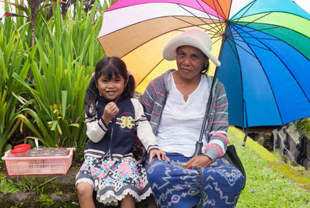 BALI - JANUARY 22. Balinese mother and daughter selling offerings to pilgrims at Mother Temple in Besakih on January 22, 2012 in Bali, Indonesia. All family members, young and old, participate is the business.のeditorial素材