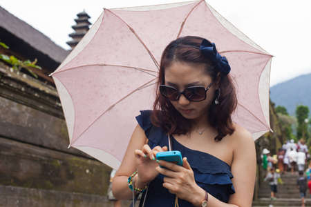 BALI - JANUARY 22. Korean visitor with umbrella at Mother Temple in Besakih on January 22, 2012 in Bali, Indonesia. The hindu temple is the largest and most visited by pilgrims and tourists.のeditorial素材
