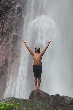 Man at waterfall raising his hands in feeling closer to natureの写真素材