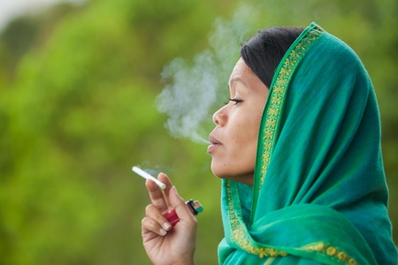 South-east asian woman with head dress smokingの写真素材