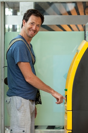 Young caucasian man withdrawing money at ATMの写真素材