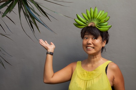 Happy and healthy woman with banana crown on her headの写真素材
