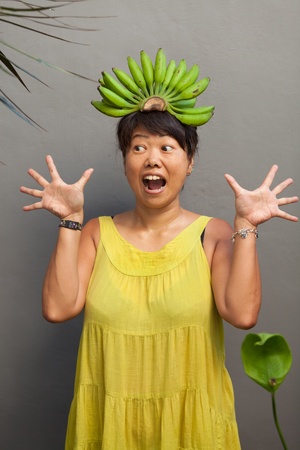 Happy and healthy woman with banana crown on her headの写真素材