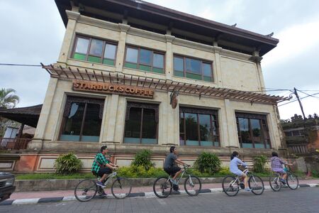BALI - FEBRUARY 3. Young people cycling past starbucks coffee in Ubud on February 3, 2012 in Bali, Indonesia. There are 72 starbucks store in all of Indonesia.のeditorial素材
