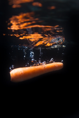 Carrot splashing into fresh water on black backgroundの写真素材