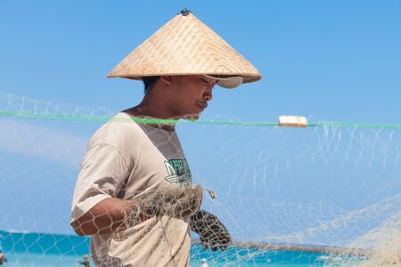 BALI - FEBRUARY 13. Fishermen cleaning nets on beach on February 13, 2012 in Bali, Indonesia. Fisheries Minister Fadel Muhammad said Indonesia set to become world's largest fish producer in 2015.のeditorial素材