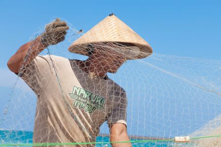BALI - FEBRUARY 13. Fishermen cleaning nets on beach on February 13, 2012 in Bali, Indonesia. Fisheries Minister Fadel Muhammad said Indonesia set to become world's largest fish producer in 2015.のeditorial素材