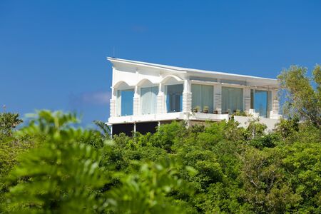 White residential house above the tree tops in tropical Bali, Indonesiaのeditorial素材