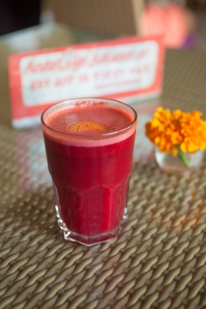 Full glass of beetroot and carrot juice decorated with flower in vegetarian restaurantの写真素材