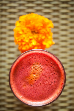 Aerial view of glass of beetroot and carrot juice decorated with flower in vegetarian restaurantの写真素材