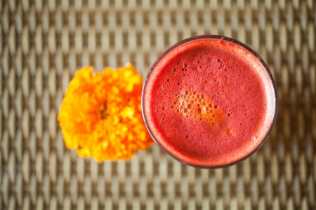 Aerial view of glass of beetroot and carrot juice decorated with flower in vegetarian restaurantの写真素材