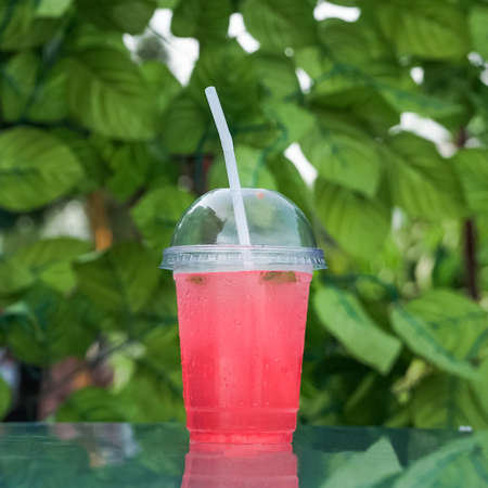 red lemonade in plastic disposable glass on a glass tableの写真素材