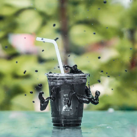 Melted Black chocolate dropping out of glass on a glass tableの写真素材