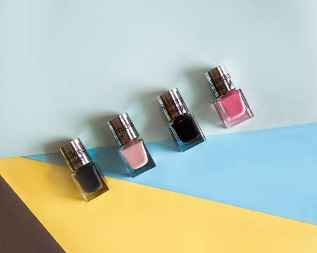 Colorful, bright and glittery nail polish bottles on a yellow and blue background.Manicure tools, beauty, nail art concept.の写真素材