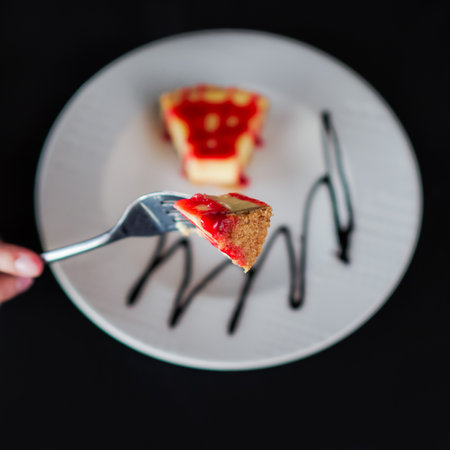 Cheese cake with strawberry topping and chocolate dressing on a wooden tableの写真素材