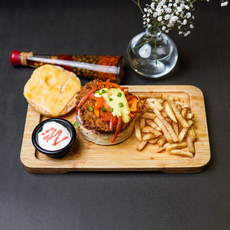 Beef Burger olive on top with fries and cheese in a wooden tray with mayo sauce and top removedの写真素材