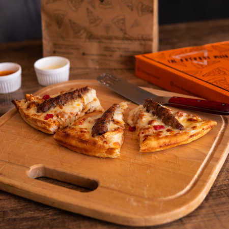 Seekh Kabab Pizza with Chicken Kabab and Reg chili with cheese extra topping with chili and garlic mayo sauce in a pizza dish on a wooden tableの写真素材