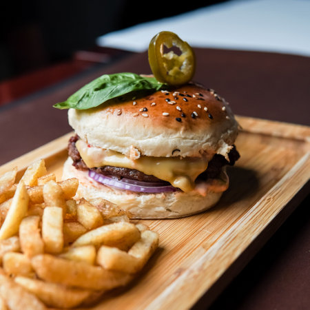 Beef Burger olive on top with fries and cheese in a wooden trayの写真素材