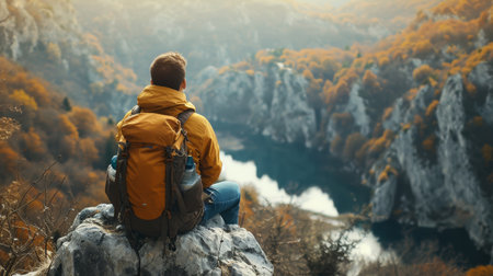 Man With Backpack Sitting on Top of a Mountainの素材