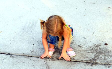 A little blonde girl with pigtails playing in the dirtの写真素材