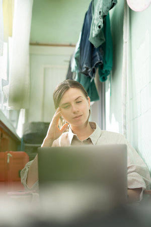 A young woman works remotely on a computer from homeの写真素材