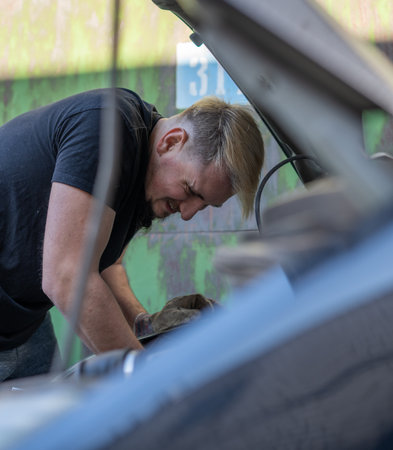 The mechanic repairs the car under the hoodの写真素材