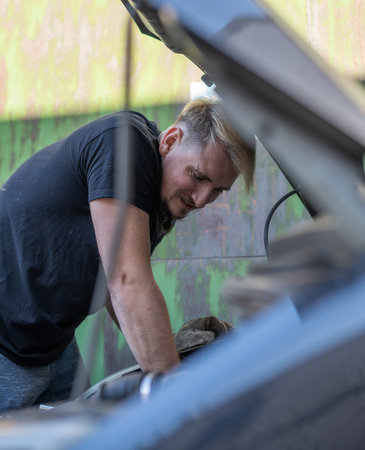 The mechanic repairs the car under the hoodの写真素材