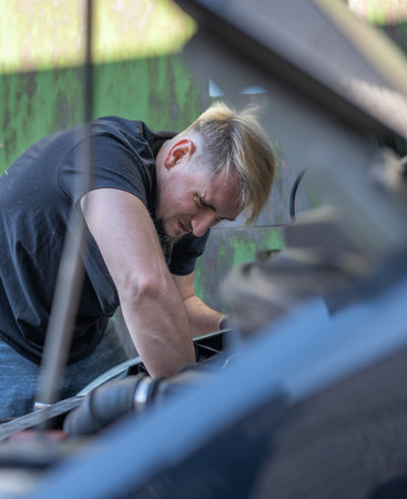 The mechanic repairs the car under the hoodの写真素材