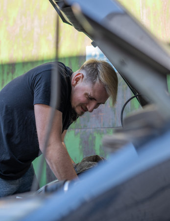 The mechanic repairs the car under the hoodの写真素材