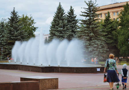 Woman and child go to the fountain in the parkの写真素材