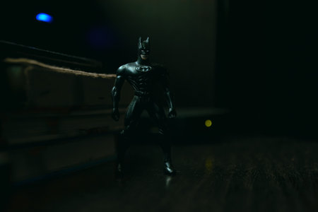 Kopeysk, Russia - August 10, 2021. Batman toy stands next to books and lights on a dark backgroundのeditorial素材