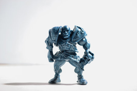 A figurine of an aggressive and vicious bald warrior in armor with a skull stands on a white backgroundの写真素材